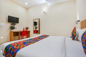 a bedroom with a white bed with a colorful blanket at FabHotel GK Residency in New Delhi