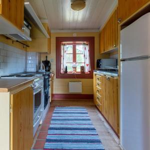 a kitchen with wooden cabinets and a rug on the floor at Traditionell Timmerstuga - Mora, Gesunda in Sollerön