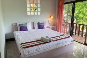 1 cama grande en un dormitorio con balcón en Phuchomjan Resort, en Mae Hong Son