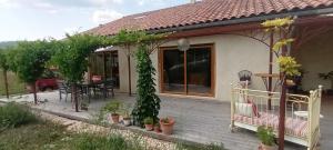 Casa con terraza de madera con mesa y sillas en Lâche prise en Les Mages