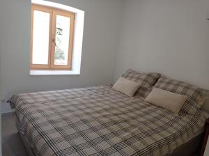 ein Bett mit einer karierten Decke und einem Fenster in der Unterkunft Heritage 4-star Studio Apartment Pitve Hvar in Jelsa