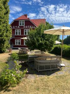 un hôtel avec des bancs et un parasol devant lui dans l'établissement Göta Hotell, à Borensberg