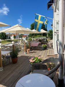 a wooden deck with tables and chairs and a flag at Göta Hotell in Borensberg