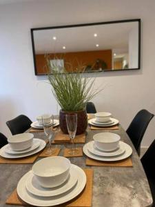 a table with plates and bowls and glasses on it at Paramount city living 105 in Swindon