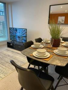 a dining room with a table with chairs and a tv at Paramount city living 105 in Swindon