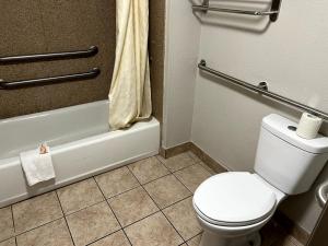 a bathroom with a white toilet and a bath tub at Budget Plaza Motel in Brooklyn Park