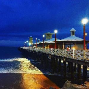 ein Pier mit einem Gebäude auf dem Wasser in der Nacht in der Unterkunft Localização Perfeita, Hotel, Completo, Limp.Diária in Fortaleza