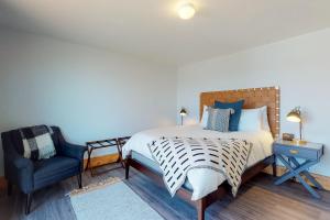 a bedroom with a bed and a blue chair at Cape Cod Cottages - #2 in Waldport