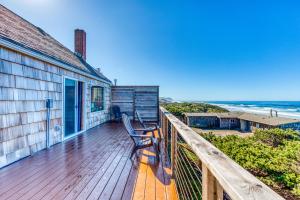 a house with a bench on a deck overlooking the ocean at Cape Cod Cottages - #2 in Waldport