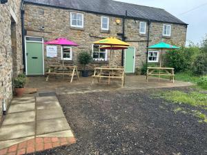 un patio con tavoli e ombrelloni di fronte a un edificio di La Fattoria a Durham