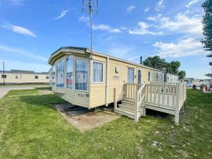 濱海克拉克頓的住宿－8 Berth Caravan For Hire Near Clacton-on-sea In Essex Ref 26287e，坐在草地上的黄色小房子