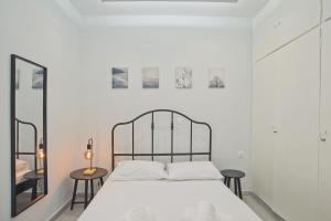 a white bedroom with a bed and two tables at Sofias Home in Piraeus