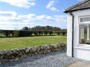 a stone wall next to a building with a grass field at Blackloch in Gatehouse of Fleet