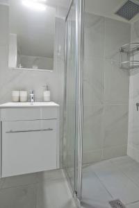 a white bathroom with a shower and a sink at Sofias Home in Piraeus