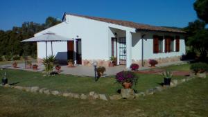 a white house with an umbrella in a yard at B&B Le Vele Teulada in Teulada