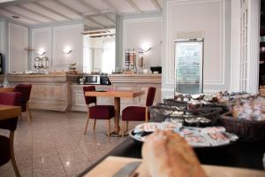 a room with tables and chairs and a kitchen at Hotel Le Continental in Forges-les-Eaux