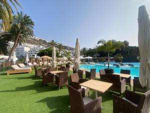 een resort met tafels en stoelen en een zwembad bij Modern Duplex apartment near swimming pool in Mogán