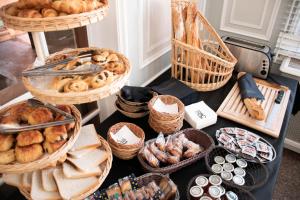 a table with baskets of bread and baskets of pastries at Hotel Le Continental in Forges-les-Eaux +15 photos