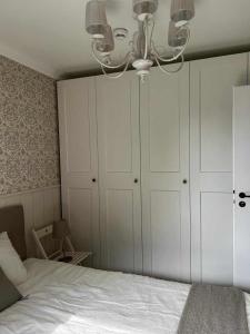 a bedroom with a bed with white cabinets and a chandelier at Apartament nad Zegrzem 206 Luksus in Serock