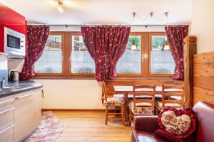 a kitchen with red curtains and a table and chairs at Cesa San Florian Appartamento 2 in Canazei