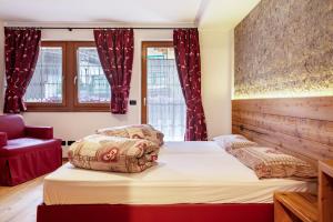 1 dormitorio con 2 camas y silla roja en Cesa San Florian Appartamento 2 en Canazei