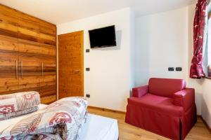 1 dormitorio con 1 cama y 1 silla roja en Cesa San Florian Appartamento 2, en Canazei