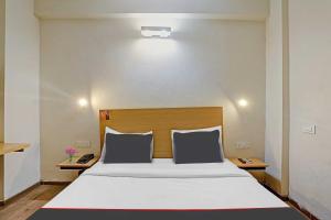 - une chambre avec un grand lit blanc et une tête de lit en bois dans l'établissement Capital O Mt Corporate Stays Near Iskcon Temple Noida, à Indirapuram