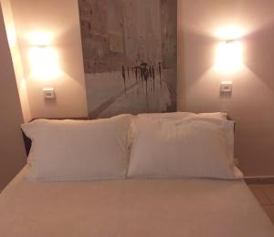 a bed with white pillows in a bedroom with two lights at THSTUDIOS Its the best in Faraí