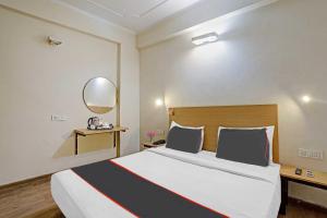 - une chambre avec un grand lit et un miroir dans l'établissement Capital O Mt Corporate Stays Near Iskcon Temple Noida, à Indirapuram