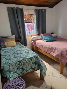 1 dormitorio con 2 camas y ventana en Ilhabela Casa Família Feliz, en Ilhabela