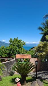 un jardín con una pared de retención y una palmera en Ilhabela Casa Família Feliz, en Ilhabela