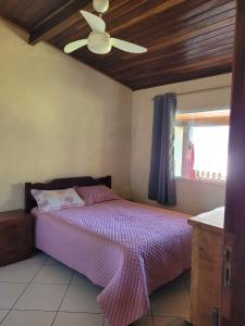 a bedroom with a bed and a ceiling fan at Ilhabela Casa Família Feliz in Ilhabela