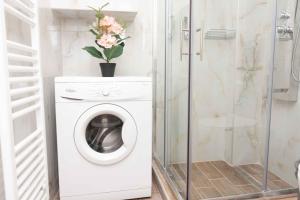 a white washing machine in a bathroom with a shower at Olga's Luxury Apartment-Thessaloniki Centre in Thessaloniki