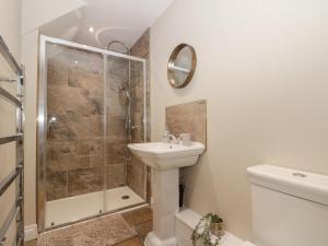 a white bathroom with a shower and a sink at Bullamoor Barn in Northallerton