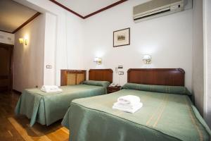 two beds in a room with green sheets at Pensión Carrera in Madrid