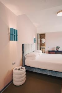- une chambre avec un grand lit blanc et un tabouret dans l'établissement Moderno Hotel Roma, à Rome