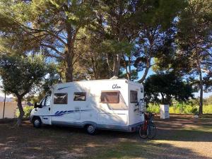 a white caravan parked in a field next to trees at Camping Cambrils Caban in Cambrils