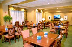 a restaurant with wooden tables and chairs and a flat screen tv at Hampton Inn Calera in Calera