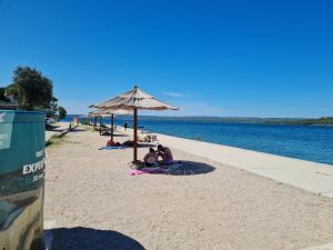 a group of people laying on the beach under an umbrella at Apartments Bosnjak in Šibenik