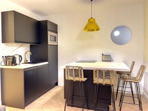 Una cocina con encimera y taburetes en una habitación. en Appartement avec balcon Le nid doré - PLACE MORNY, en Deauville 3 fotos más