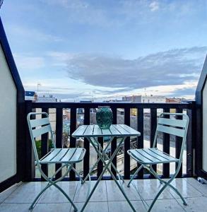 un tavolo e due sedie su un balcone con vista sull'oceano di Appartement avec balcon Le nid doré - PLACE MORNY a Deauville