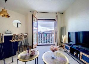 un soggiorno con 2 tavoli e una TV a schermo piatto di Appartement avec balcon Le nid doré - PLACE MORNY a Deauville