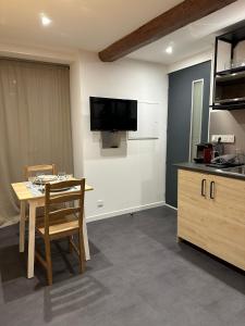 a kitchen with a table and a tv on the wall at Studio RDC La Tour in Saint-Étienne-de-Tinée