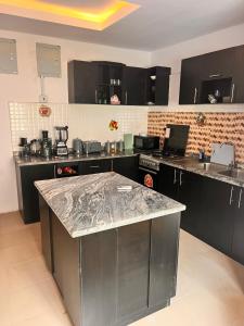 a kitchen with black cabinets and a granite counter top at Treasure Park and Garden. Golf Estate. Simawa in Likosi