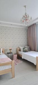 a bedroom with two beds and a chandelier at BAYHOUSE - Апартаменты в ЖК Уш Сункар in Almaty