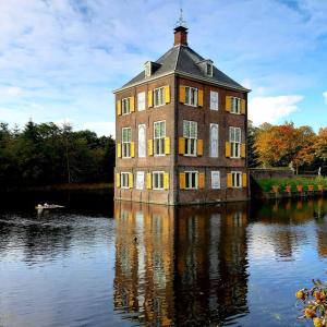 un grande edificio in mattoni in mezzo a un lago di Koetshuis aan het water 3 bedroom villa a Voorburg