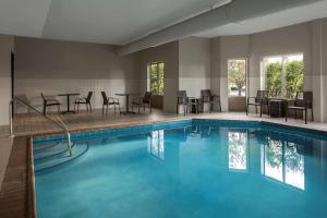 uma piscina com cadeiras e mesas num quarto de hotel em Homewood Suites by Hilton Orland Park em Orland Park