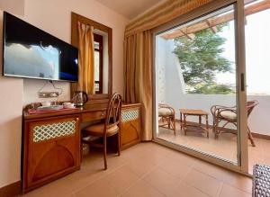 a room with a desk and a television and a table and chairs at ℂoral Bay Dream - Luxury Sunset Sea View Apartment in Sharm El Sheikh