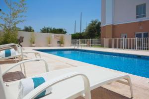 a swimming pool with two chairs next to a building at Hampton Inn by Hilton Ciudad Victoria in Ciudad Victoria
