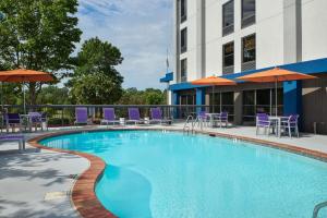 a swimming pool with chairs and umbrellas next to a building at Hampton Inn Clemson in Clemson
